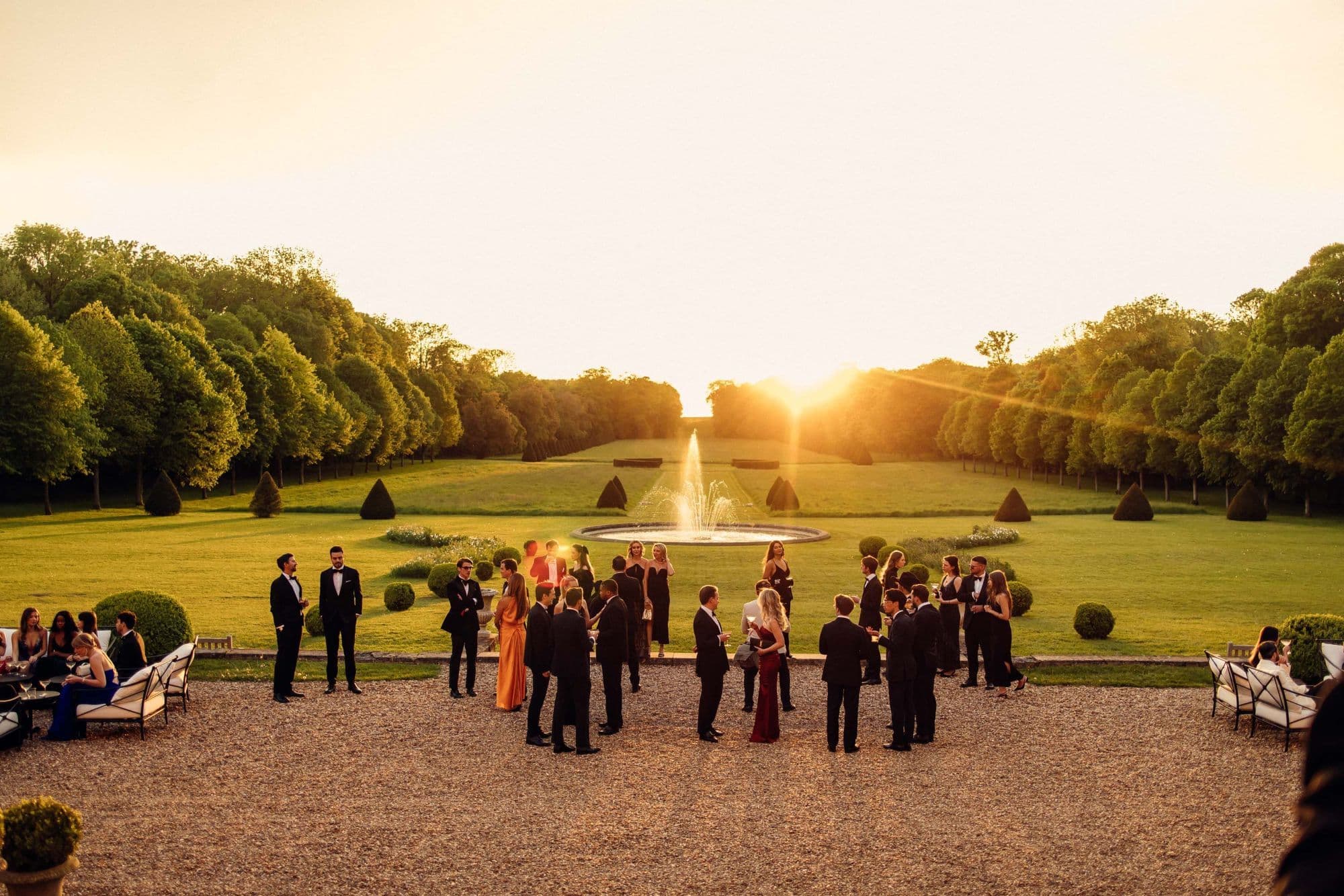 Guests in evening dress on a formal garden terrace at sunset