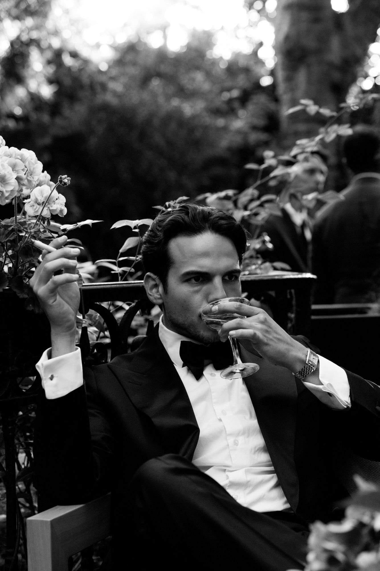 Black and white portrait of a guest in a dinner jacket, holding a coupe